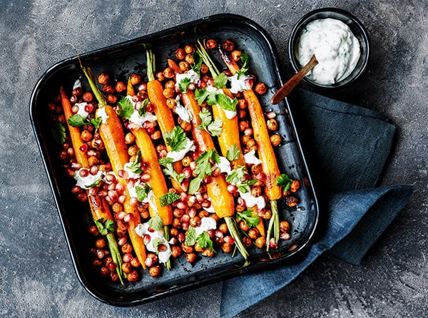 Bagte gulerødder og kikærter i fad med dressing og urter ---