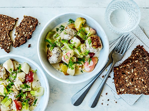 To skåle med frikadeller og kartoffelsalat samt knækbrød og rugbrød ved siden af