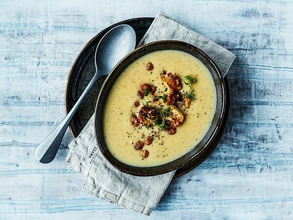 En skål kartoffelsuppe med baconstykker og krydderurter på toppen.