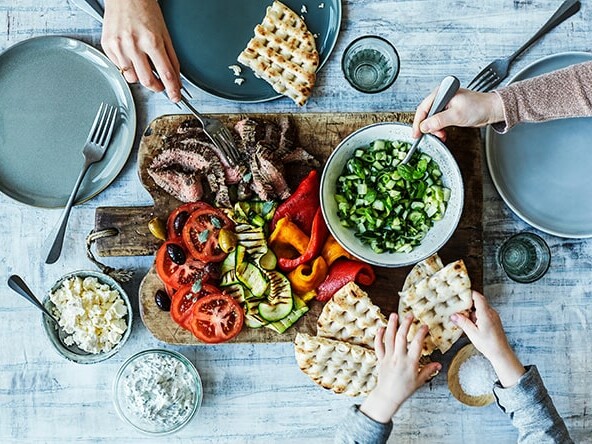 Familie deler en skøn middag med kød, grøntsager og brød