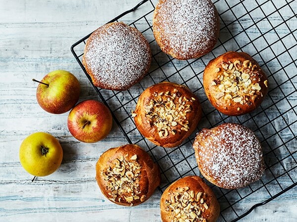 Æbleboller med nødder og flormelis på bagerist ved siden af æbler.