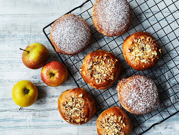 Æbleboller med nødder og flormelis på bagerist ved siden af æbler.