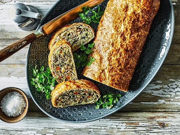 Vegetarisk nøddepostej skåret i skiver på et fad med persille og kniv