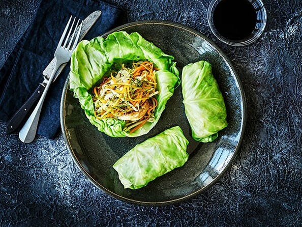 To kålruller og en åben kålblom med grøntsager på en tallerken