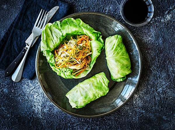 To kålruller og en åben kålblom med grøntsager på en tallerken