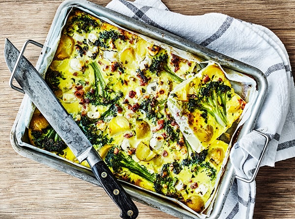 En stor kartoffelfrittata i en bageform med en kniv ved siden af