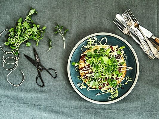 En tallerken med salat, urter, saks og bestik på en dug