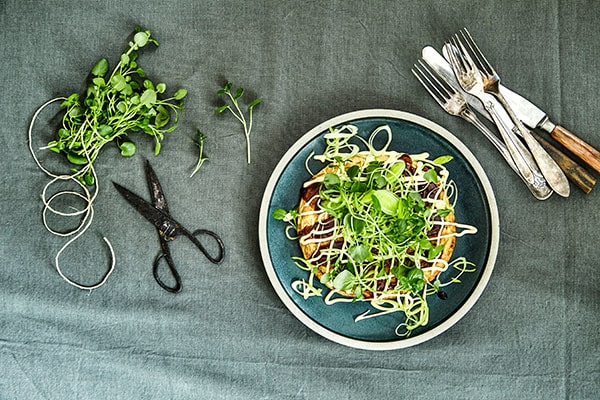 En tallerken med salat, urter, saks og bestik på en dug