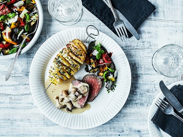 Tallerken med skiver af kartoffel, kød og grøntsager.