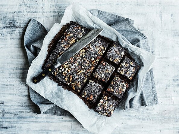 En chokoladekage med nødder og en kniv på bagepapir