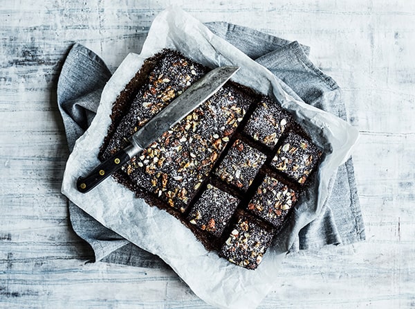 En chokoladekage med nødder og en kniv på bagepapir