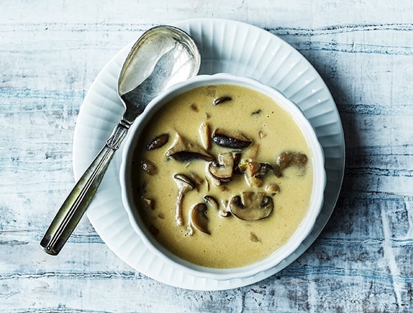 En skål med cremet svampesuppe og svampe på en hvid tallerken