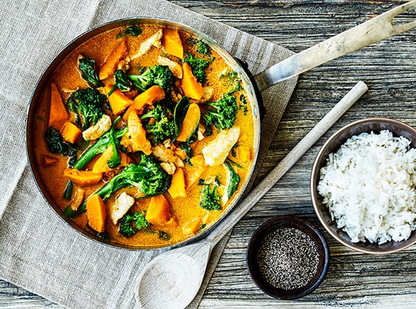 Farverig gryde med kylling, søde kartofler, grønkål, serveret med ris