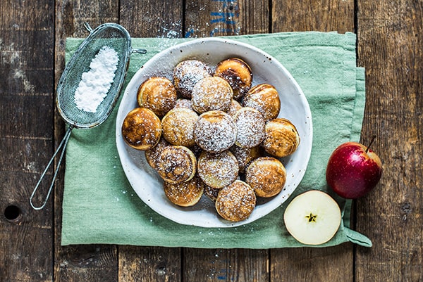 Hvid tallerken med æbleskiver og flormelis på rustikt træbord med æble og grønt klæde