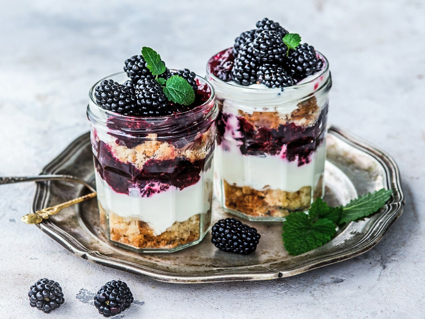 To glas med lag af hindbær, kage og flødeskum, toppet med friske hindbær