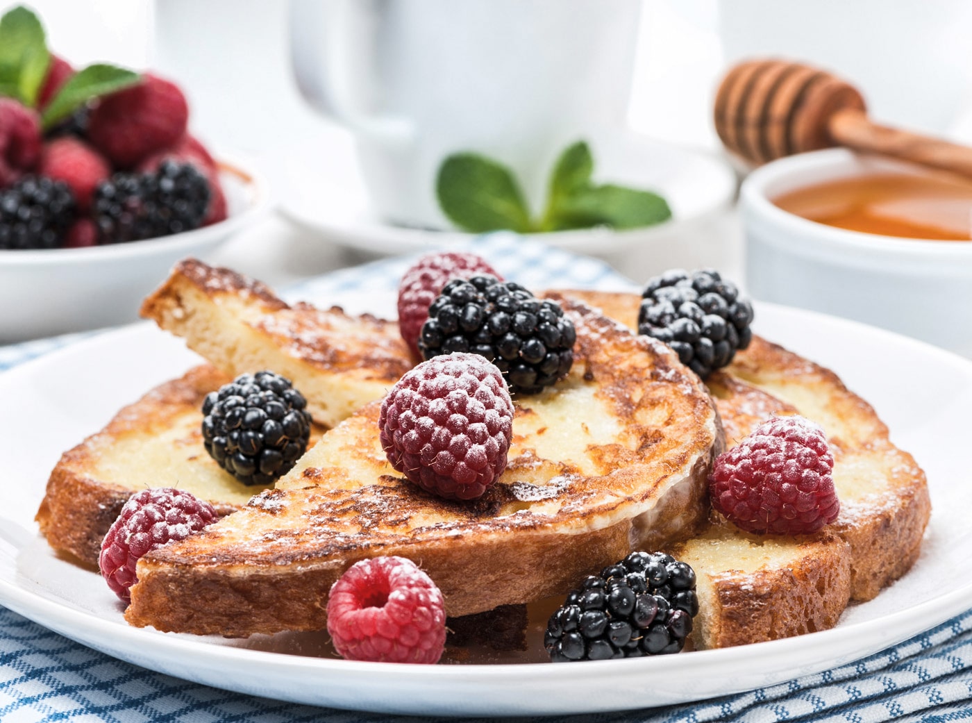 Lækker fransk toast toppet med friske hindbær og brombær på en tallerken.