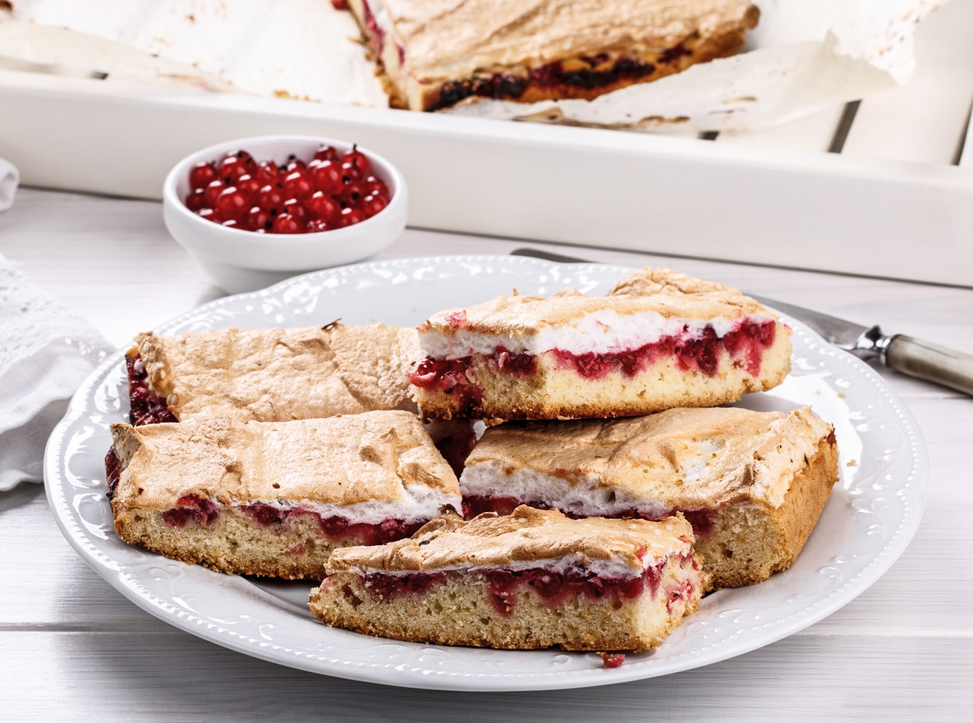 Stykker af frugtkage med marengs og røde bær på en tallerken