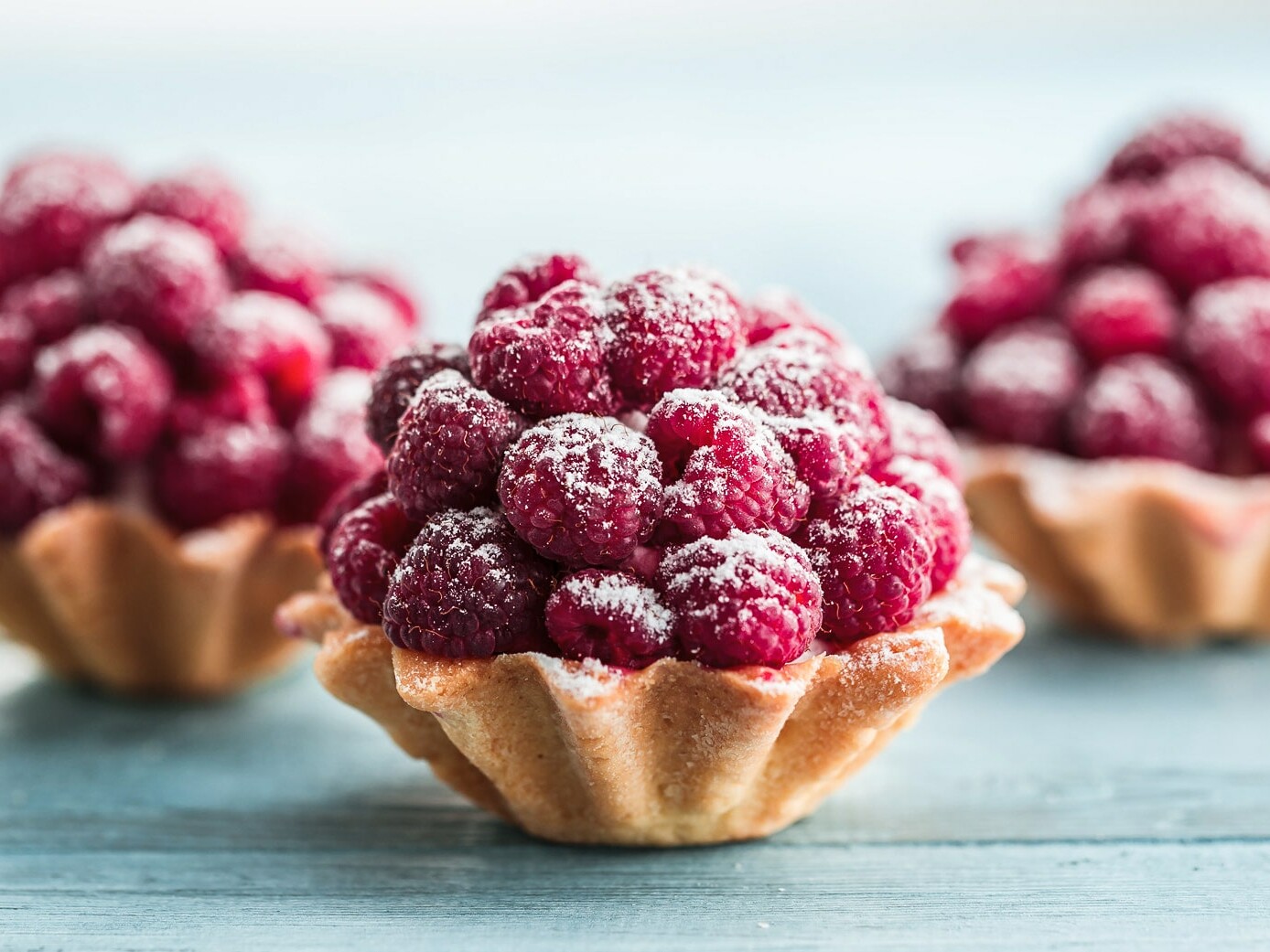 Tre små tærter med friske hindbær og flormelis
