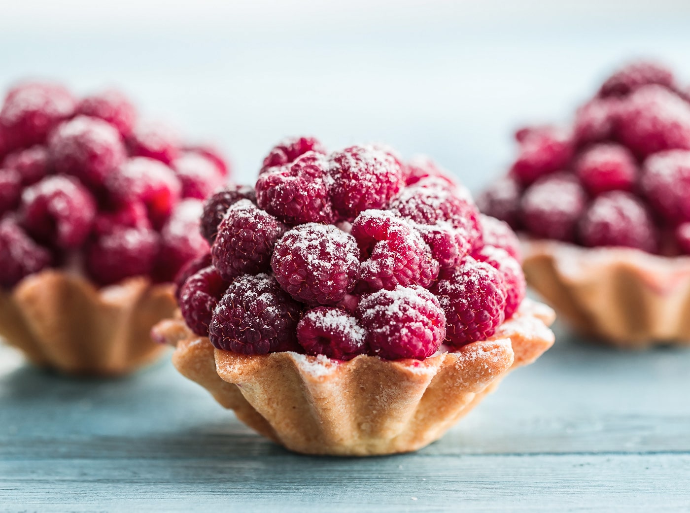 Tre små tærter med friske hindbær og flormelis