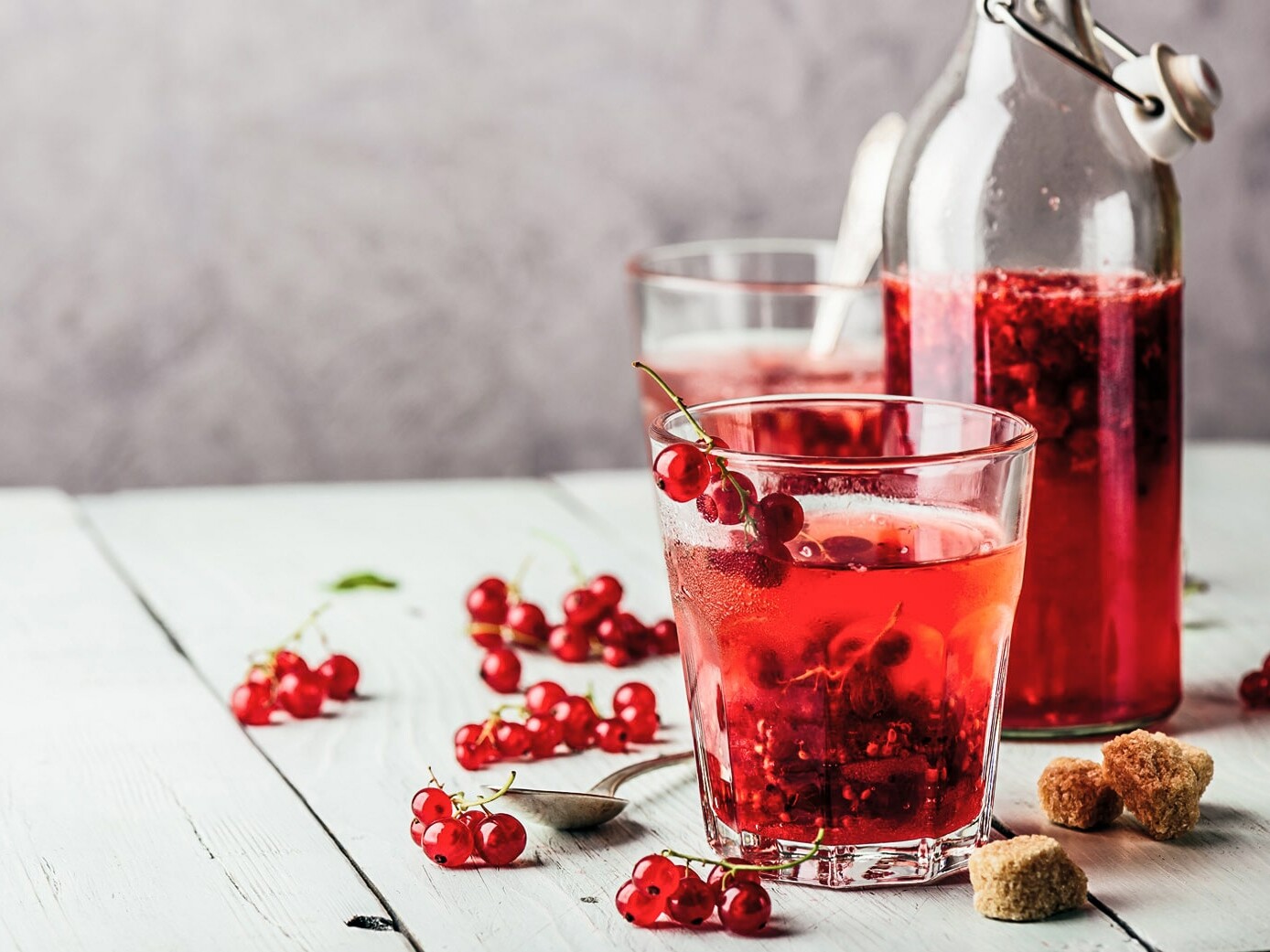 Glas med rød drik, rødvinbær og flaske
