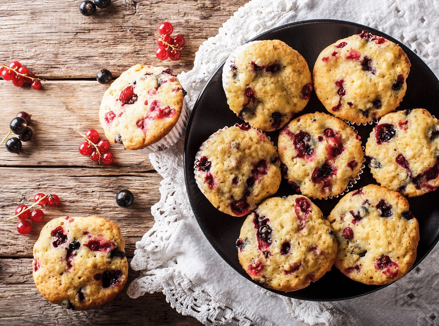 Lækre muffins med friske bær arrangeret på sort tallerken og træbord