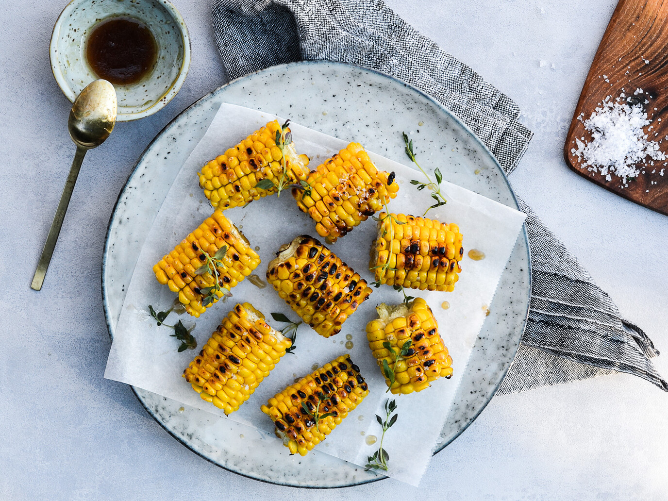 Grillede majskolber med timian på en tallerken med sauce