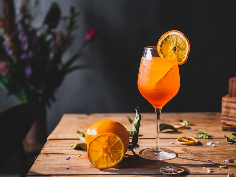 Appelsindrink i glas med skive på træbord med appelsin