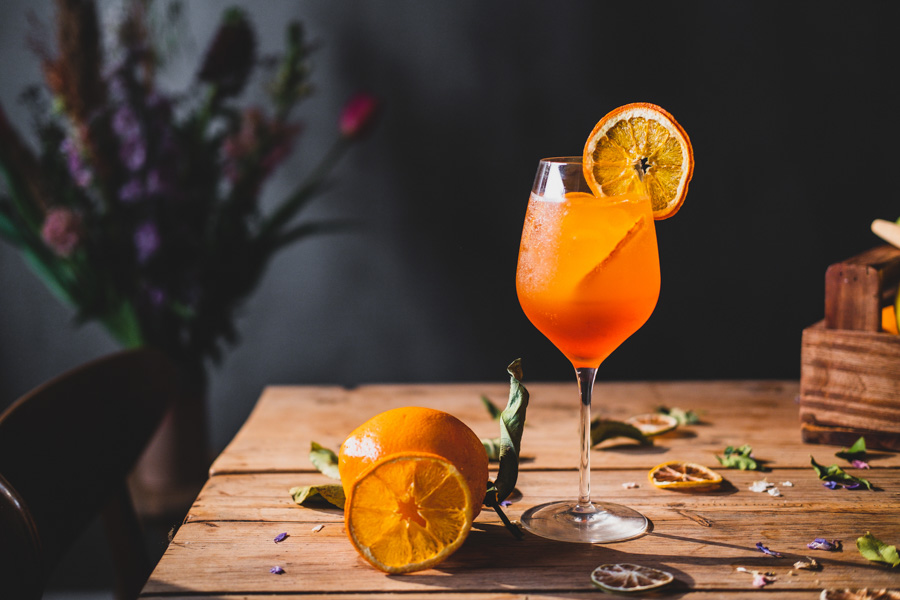 Appelsindrink i glas med skive på træbord med appelsin