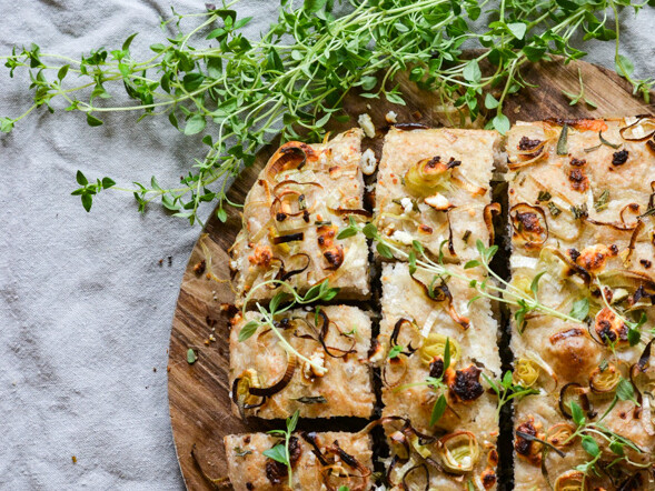 Focaccia-brød med løg og urter på et træbræt