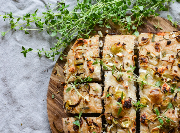 Focaccia-brød med løg og urter på et træbræt
