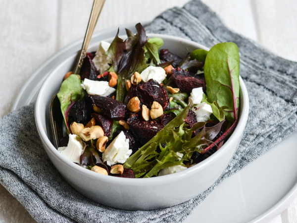 En skål med salat, rødbeder, feta og nødder på gråt stof