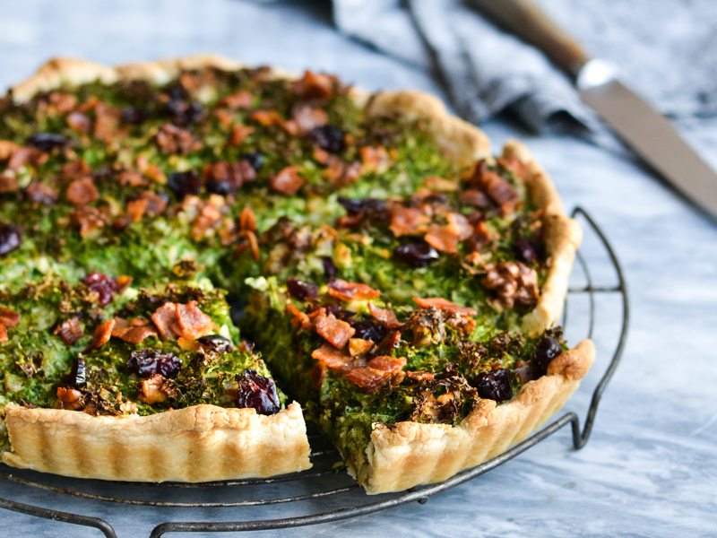 En hjemmelavet tærte med grønne grøntsager og sprød topping på et bagerist.