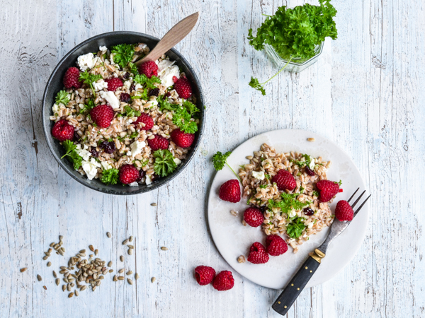 Skål og tallerken med perlespeltsalat, feta, hindbær og persille
