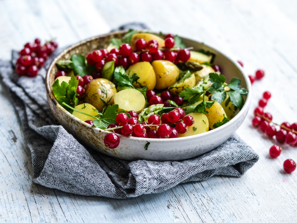 Skål med kartoffelsalat, ribs og krydderurter på en klud
