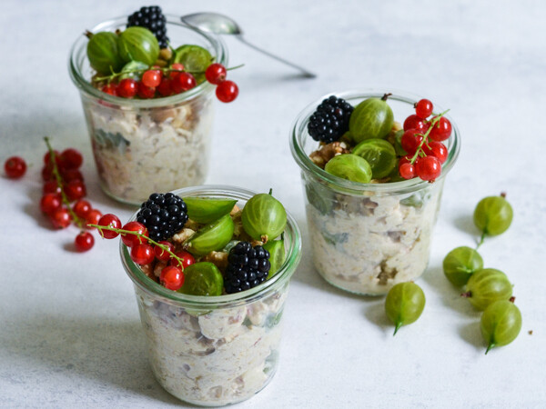 Tre glas fyldt med frugtsalat pyntet med brombær, ribs og stikkelsbær