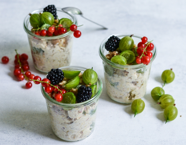 Tre glas fyldt med frugtsalat pyntet med brombær, ribs og stikkelsbær