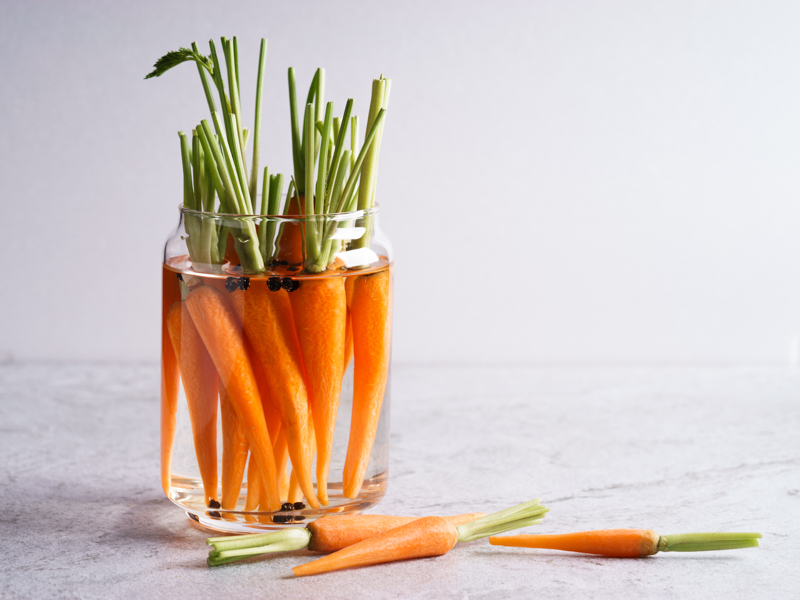 Gulerødder i glas med vand på bord