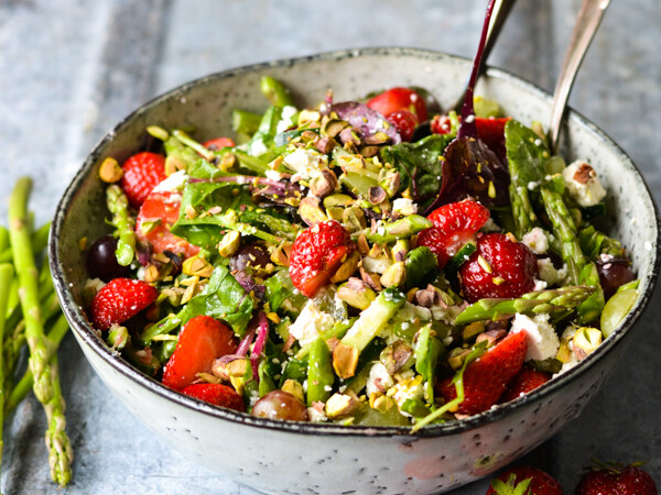 En skål med farverig salat bestående af jordbær, asparges og nødder.