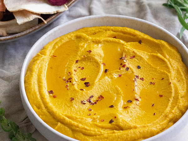 Gulerodshummus i en skål med krydderflager på toppen