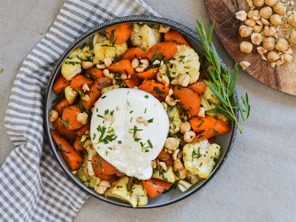 En skål med grillet blomkål, gulerødder, burrata og nødder