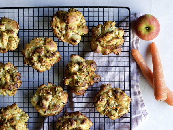 Friskbagte grøntsagsmuffins ved siden af gulerødder og et æble